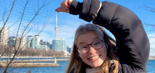 Alisa pelleilee kameralle ja nipistää horisontissa pienenä näkyvän CN Towerin sormiensa väliin.